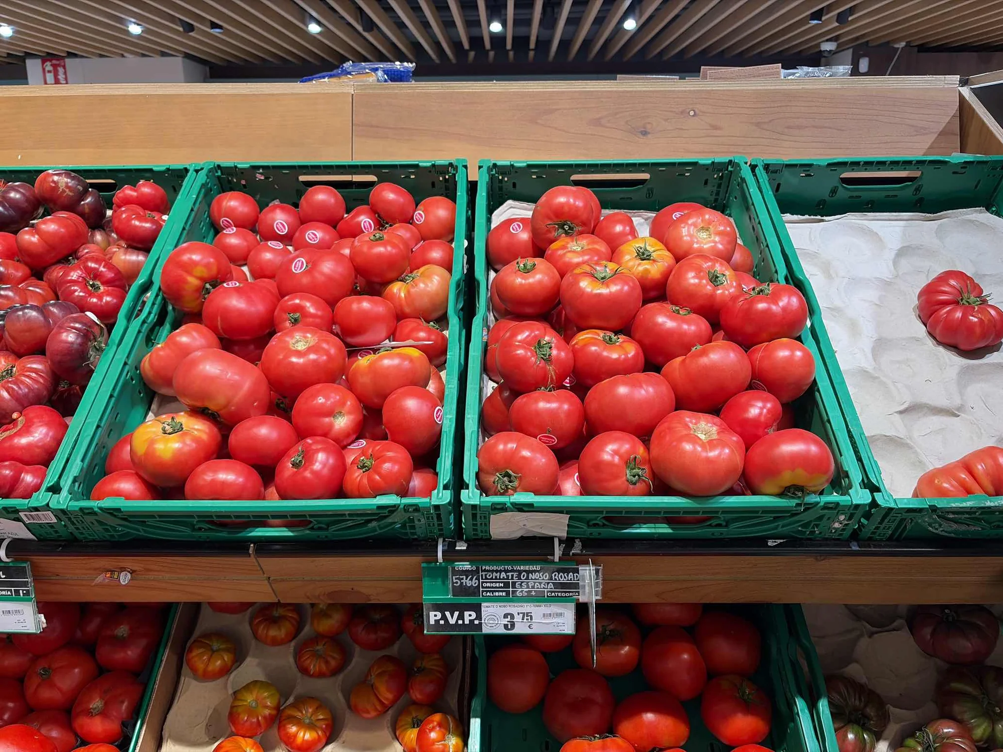 Round tomatoes displayed across two crates in the aisle